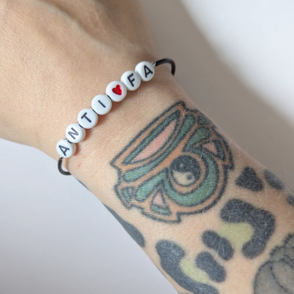 Vegan und handgemacht Armband: ANTIFA mit rotem Herz, aus Kunstleder mit Kunststoffperlen und rostfreiem Edelstahl, wasserfest, passend zu RUDE REBELs nachhaltigem, rebellischem Design.