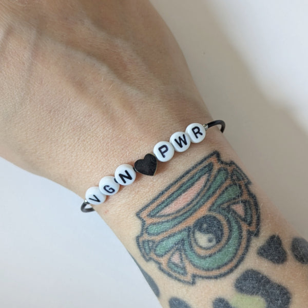 Vegan und handgemacht Armband: VEGAN POWER mit Edelstahl Herz und Peace Charm, aus Kunstlederband mit Kunststoffperlen, wasserfest und aus rostfreiem Edelstahl gefertigt.
