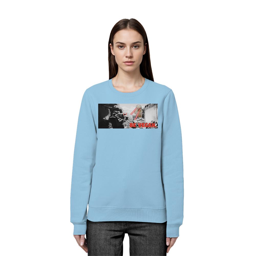 Frau trägt ein hellblaues Vegan und Bio Sweatshirt: BE VEGAN mit Berglandschaft und rotem Slogan, aus Bio-Baumwolle und recyceltem Polyester, normales Design.