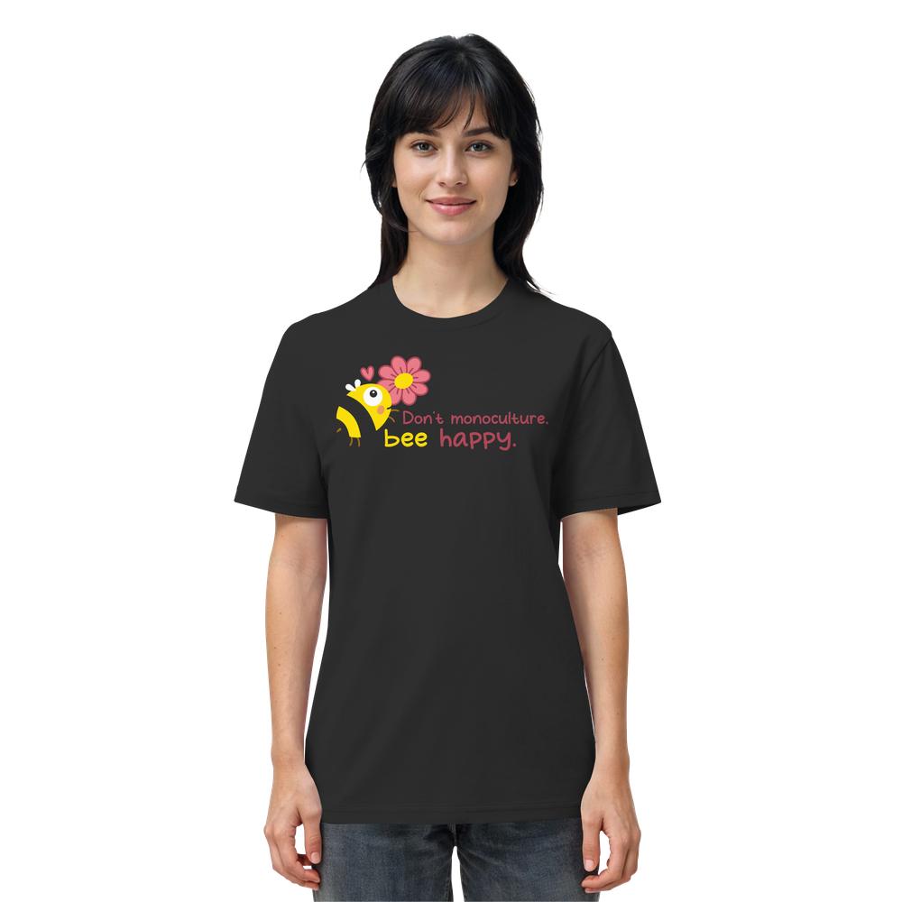 Person trägt das Vegan und Bio Unisex Shirt: Save the bees, mit fröhlicher Cartoon-Biene, rosa Blume und Slogan „Don’t monoculture. bee happy.“ auf schwarzem Hintergrund.
