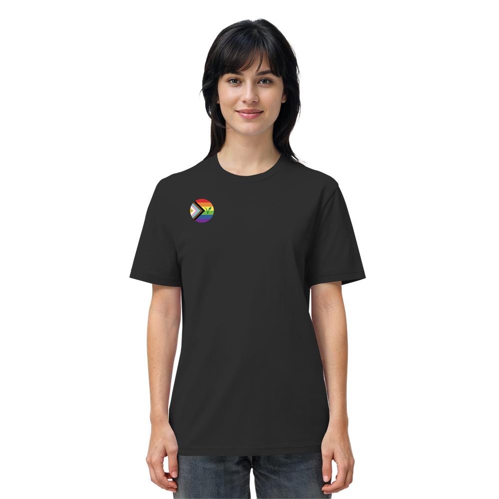 Person trägt ein schwarzes T-Shirt mit kleiner progressiver Pride-Flagge und Veganismus-V über dem Herzen. Veganes und biologisches Unisex-Shirt von RUDE REBEL.