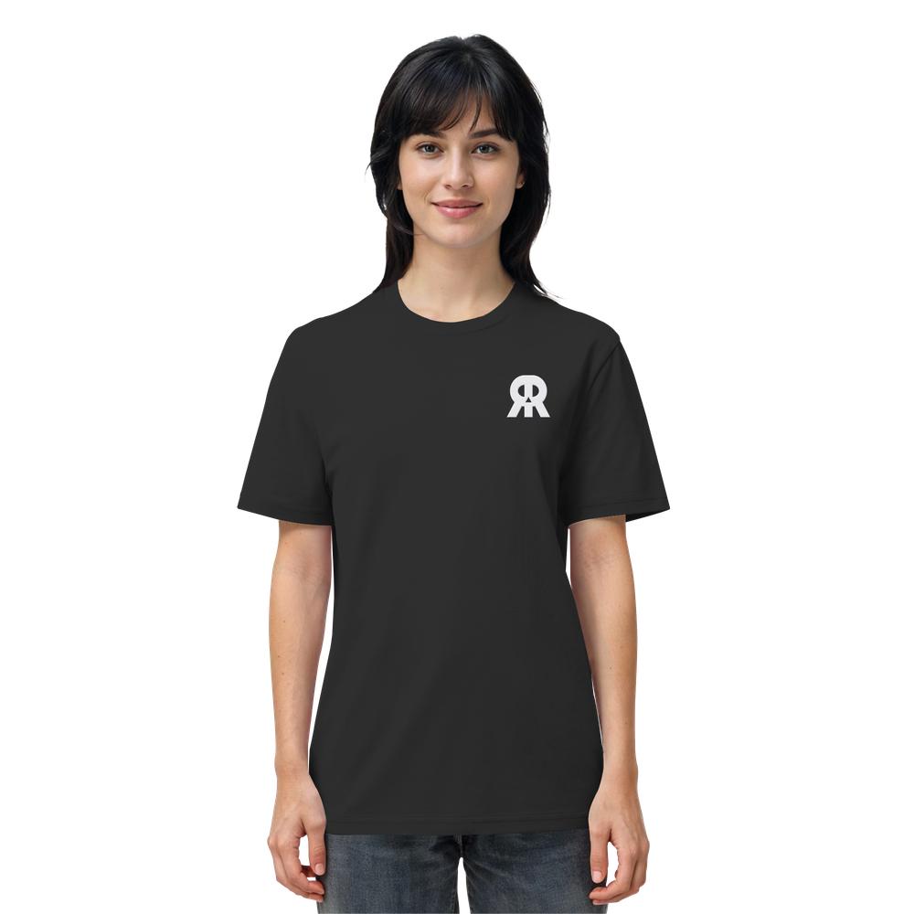 Junge Frau im schwarzen Vegan und Bio Unisex Shirt bestickt: RUDE REBEL Skull, mit kleinem weißen Logo auf der Brust, steht vor weißem Hintergrund.