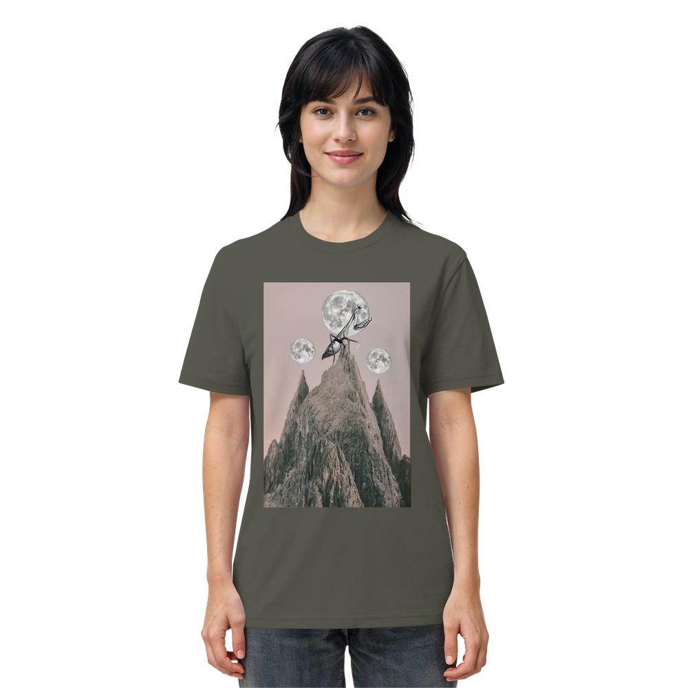 Frau trägt ein olivegrünes Vegan und Bio Unisex Shirt: Gottesanbeterin mit surrealem Druck: Berg, rosa Himmel, drei Monde, riesige Ameise mit Kletterausrüstung.